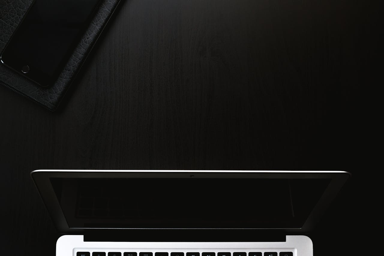 who-we-are A sleek and minimalist workspace featuring a laptop and smartphone on a dark surface.